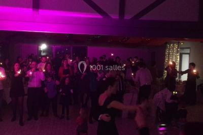 Groupe de personnes dans une salle éclairée par des lumières roses, certaines tenant des bougies.