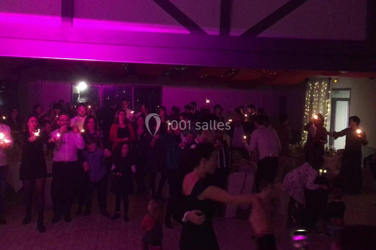 Groupe de personnes dans une salle éclairée par des lumières roses, certaines tenant des bougies.