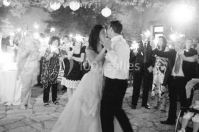 Un couple en tenue de mariage pose devant des lumières colorées dans une ambiance festive.