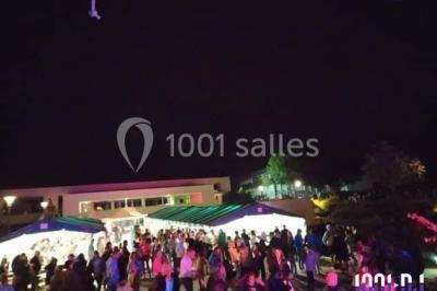 Un couple en tenue de mariage pose devant des lumières colorées dans une ambiance festive.