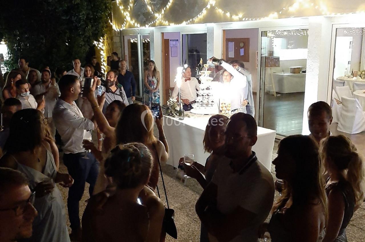 Groupe de personnes rassemblées en soirée devant une table éclairée, décorée de guirlandes lumineuses.