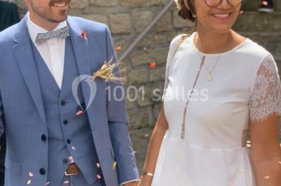 Un couple en tenue de mariage pose devant des lumières colorées dans une ambiance festive.
