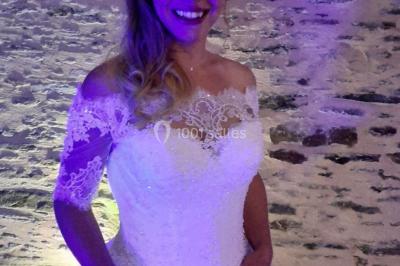 Un couple en tenue de mariage pose devant des lumières colorées dans une ambiance festive.