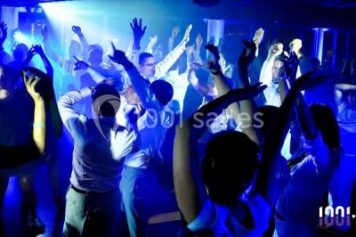 Un couple en tenue de mariage pose devant des lumières colorées dans une ambiance festive.