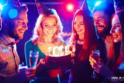 Un couple en tenue de mariage pose devant des lumières colorées dans une ambiance festive.