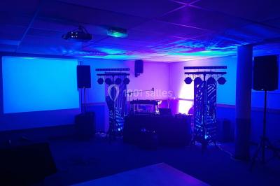 Un couple en tenue de mariage pose devant des lumières colorées dans une ambiance festive.