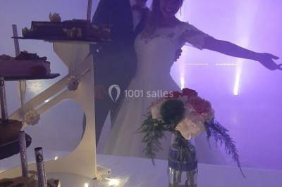 Un couple en tenue de mariage pose devant des lumières colorées dans une ambiance festive.