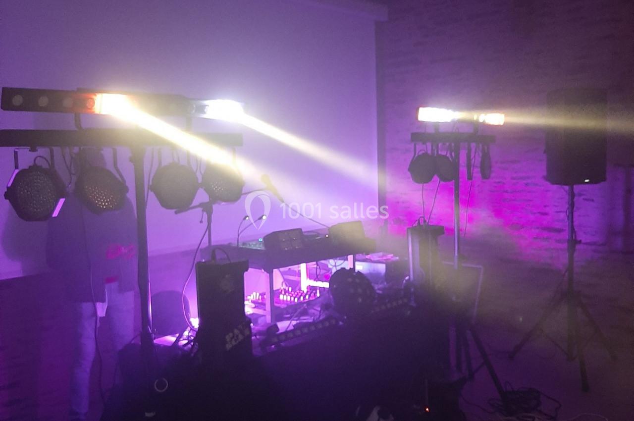 Équipement de sonorisation et éclairage installé dans une salle avec ambiance lumineuse violette.