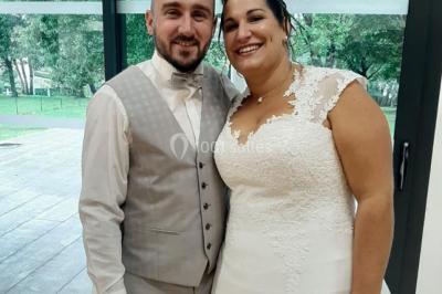 Un couple en tenue de mariage pose devant des lumières colorées dans une ambiance festive.
