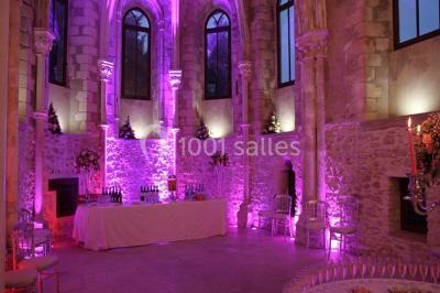 Ruelle pavée bordée de fleurs, avec un puits en pierre et des bâtiments anciens sous un ciel ensoleillé.