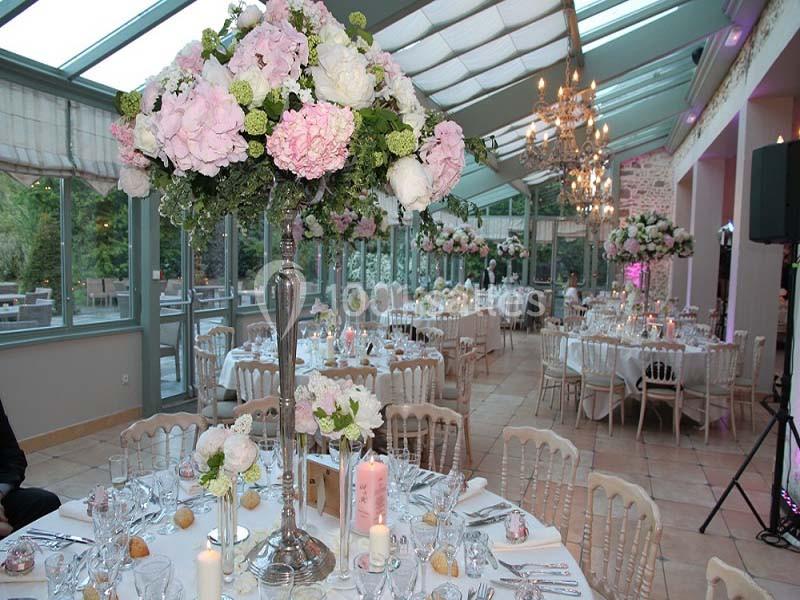 Salle de réception lumineuse décorée avec des tables élégantes et des centres de table fleuris dans des tons pastel.