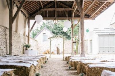 Ruelle pavée bordée de fleurs, avec un puits en pierre et des bâtiments anciens sous un ciel ensoleillé.