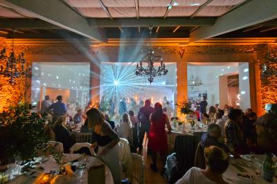 Ruelle pavée bordée de fleurs, avec un puits en pierre et des bâtiments anciens sous un ciel ensoleillé.