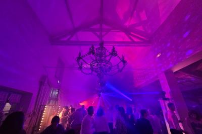 Ruelle pavée bordée de fleurs, avec un puits en pierre et des bâtiments anciens sous un ciel ensoleillé.