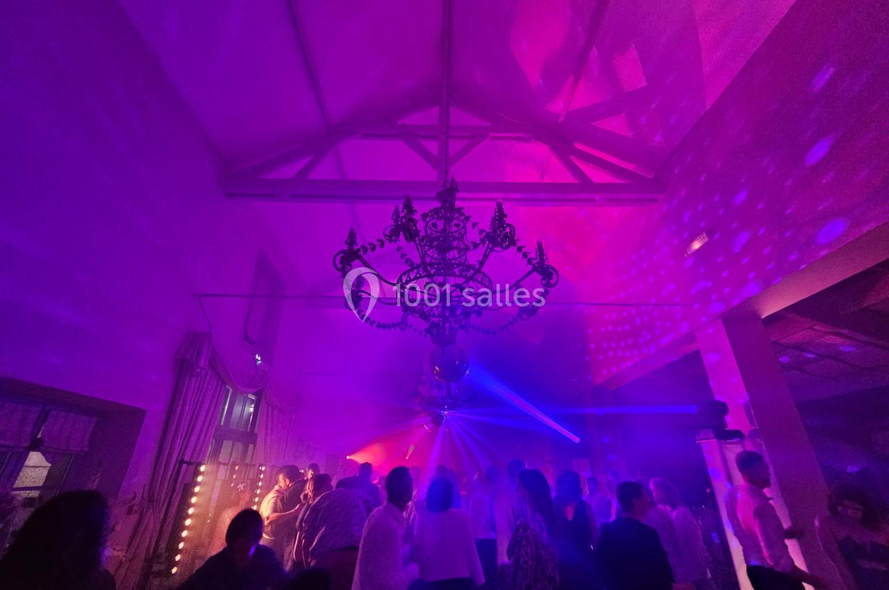 Groupe de personnes dansant sous un éclairage coloré avec un lustre imposant au plafond.