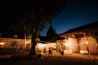 Ruelle pavée bordée de fleurs, avec un puits en pierre et des bâtiments anciens sous un ciel ensoleillé.