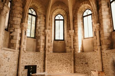 Ruelle pavée bordée de fleurs, avec un puits en pierre et des bâtiments anciens sous un ciel ensoleillé.