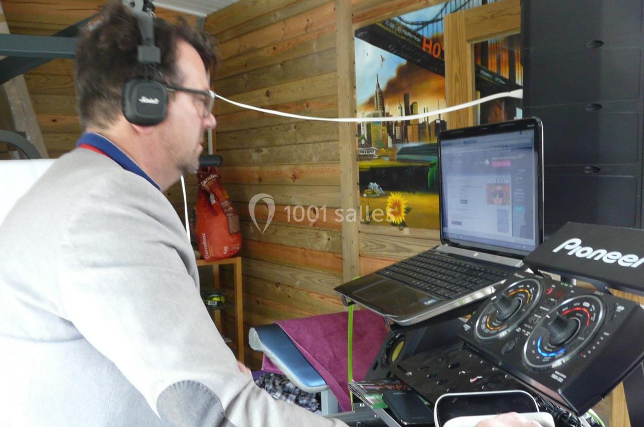 Un homme portant un casque audio utilise un équipement de DJ avec un ordinateur portable dans un espace en bois.