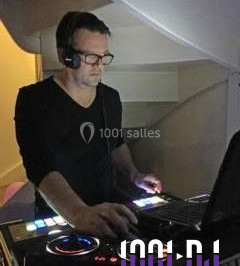 Vue d'une soirée avec un DJ en arrière-plan, des invités dans une ambiance tamisée et un écran de mixage au premier plan.