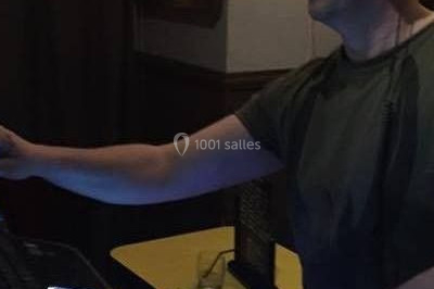 Vue d'une soirée avec un DJ en arrière-plan, des invités dans une ambiance tamisée et un écran de mixage au premier plan.