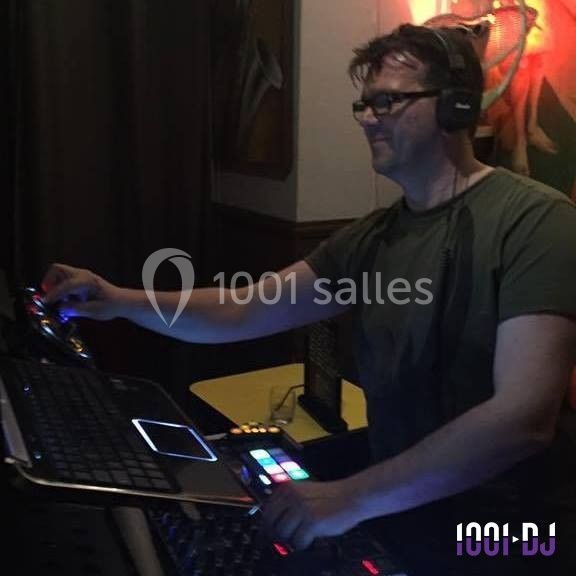 Homme portant un casque audio, mixant de la musique sur une table de mixage dans un environnement sombre.