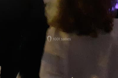 Vue d'une soirée avec un DJ en arrière-plan, des invités dans une ambiance tamisée et un écran de mixage au premier plan.