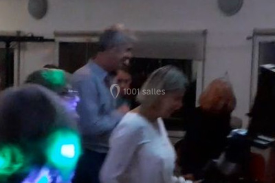 Vue d'une soirée avec un DJ en arrière-plan, des invités dans une ambiance tamisée et un écran de mixage au premier plan.