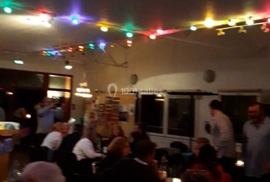 Vue d'une soirée avec un DJ en arrière-plan, des invités dans une ambiance tamisée et un écran de mixage au premier plan.