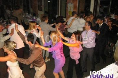 Des personnes dansent sous des guirlandes lumineuses dans une salle décorée pour une fête.