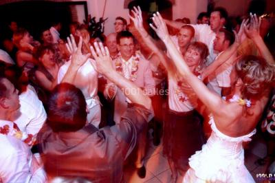 Des personnes dansent sous des guirlandes lumineuses dans une salle décorée pour une fête.