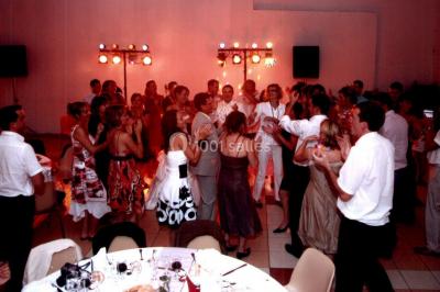 Des personnes dansent sous des guirlandes lumineuses dans une salle décorée pour une fête.