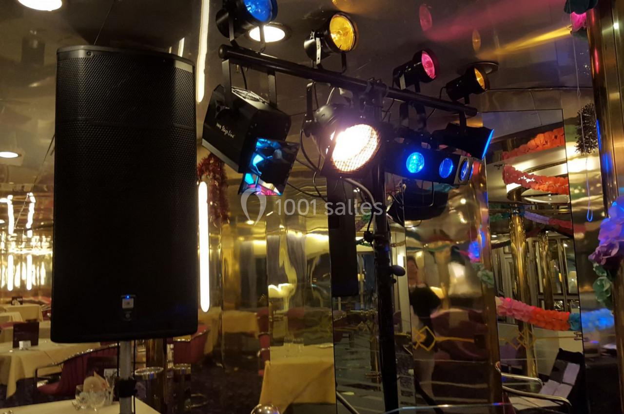 Éclairage de scène avec projecteurs colorés et haut-parleur dans une salle décorée avec des tables dressées.