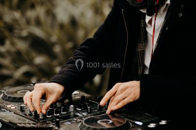 Portrait en noir et blanc d'un homme souriant avec des cheveux bouclés et une moustache, sur un fond flou naturel.
