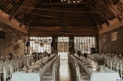 Homme souriant avec une moustache, portant une chemise sombre, devant un arrière-plan flou de verdure.