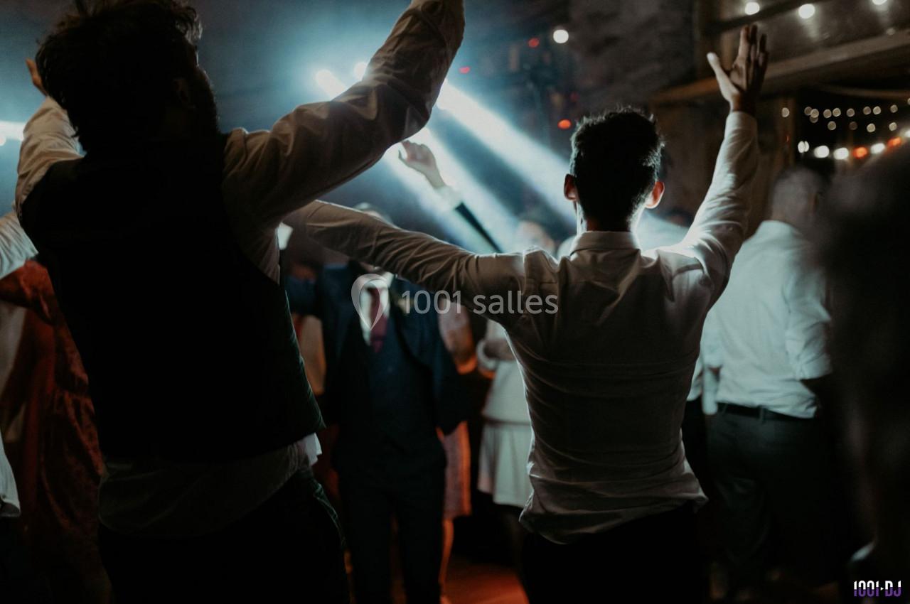 Personnes dansant dans une ambiance festive avec des jeux de lumière dans une salle sombre.