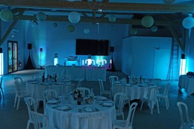 Salle de réception avec scène éclairée par des projecteurs orange, décorée de ballons suspendus.
