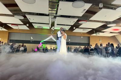 Salle de réception avec scène éclairée par des projecteurs orange, décorée de ballons suspendus.