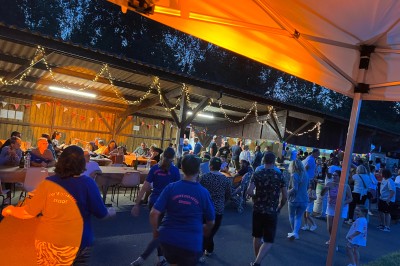 Salle de réception avec scène éclairée par des projecteurs orange, décorée de ballons suspendus.