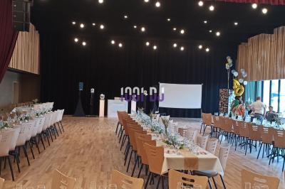 Salle décorée avec des lumières colorées, une table blanche au centre et un écran noir en arrière-plan.