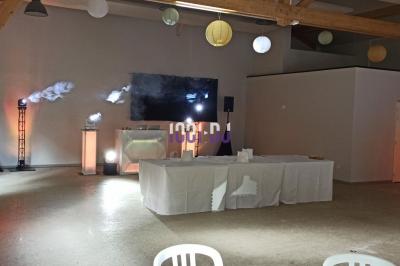 Salle décorée avec des lumières colorées, une table blanche au centre et un écran noir en arrière-plan.