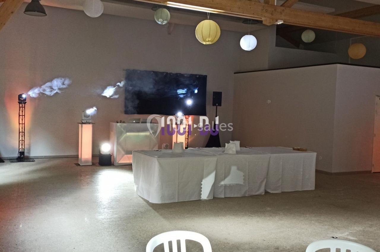 Salle décorée avec des lumières colorées, une table blanche au centre et un écran noir en arrière-plan.