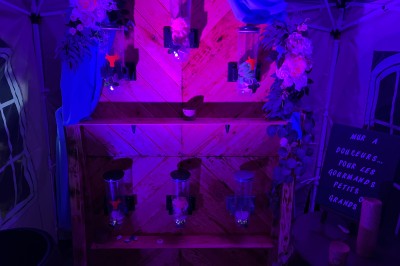 Salle décorée avec des lumières colorées, une table blanche au centre et un écran noir en arrière-plan.