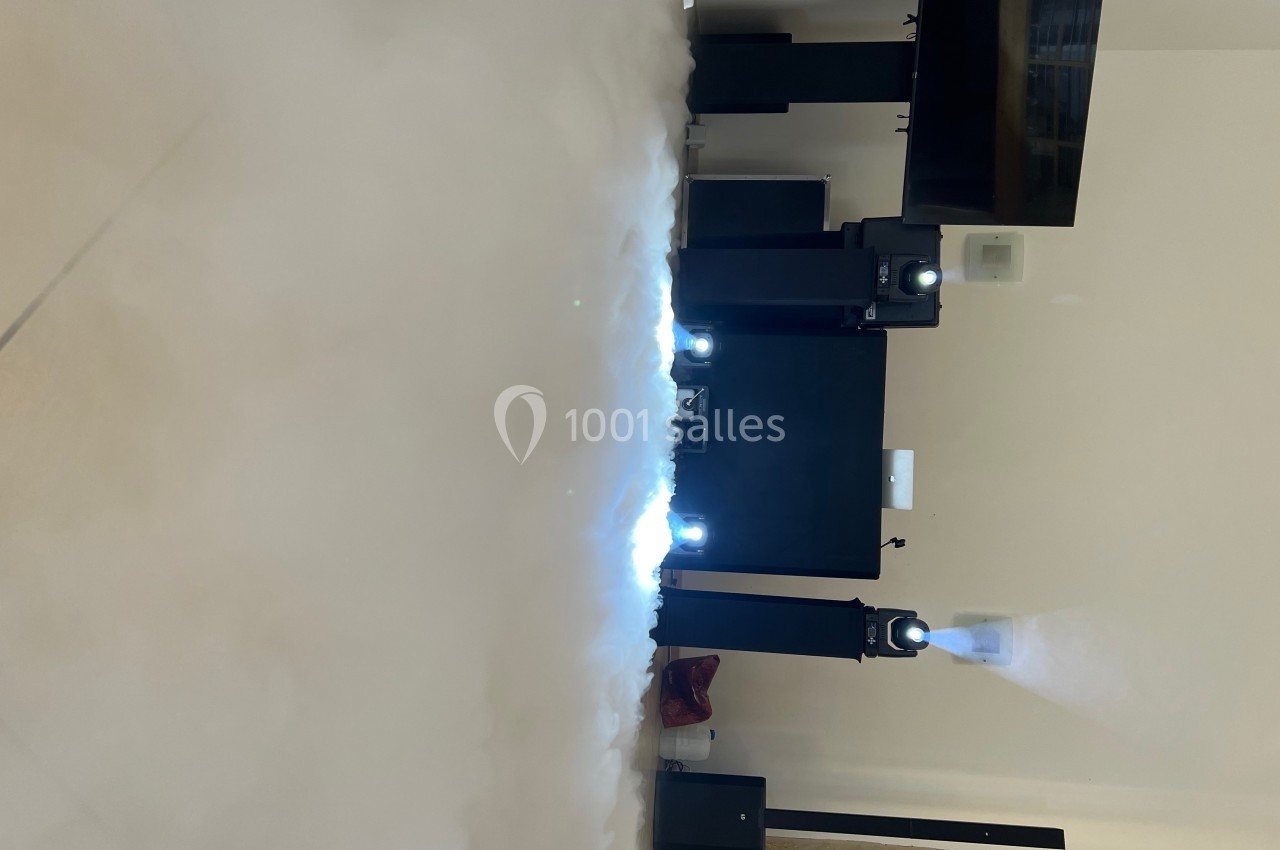 Installation de projecteurs lumineux et d'équipements audio dans une pièce avec un sol recouvert de fumée blanche.