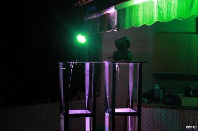 Équipement de sonorisation installé en extérieur sous une tente blanche, entouré de végétation.