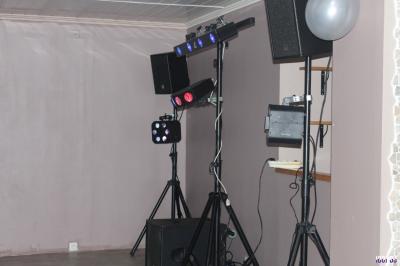 Équipement de sonorisation installé en extérieur sous une tente blanche, entouré de végétation.