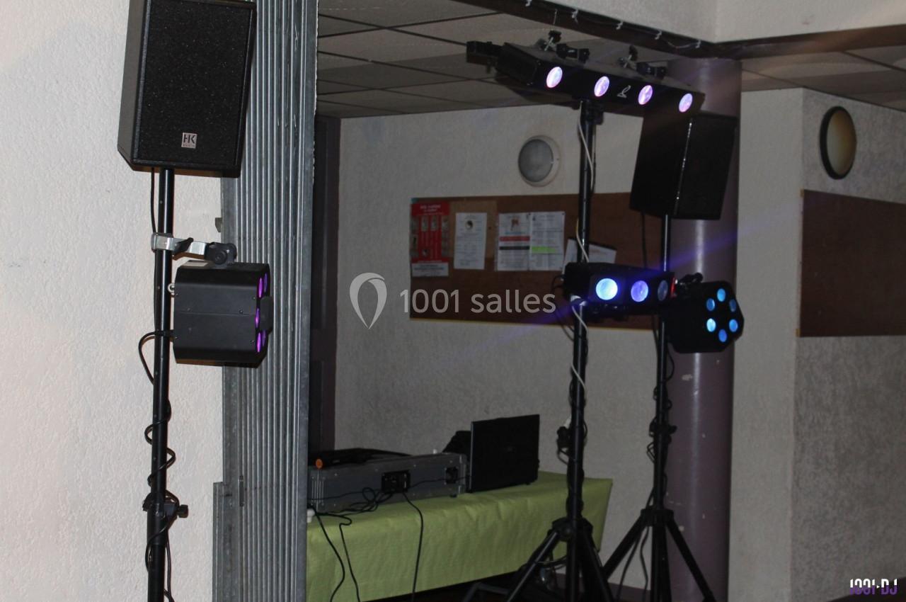 Équipement de sonorisation et éclairage installé dans une salle, avec table de mixage et projecteurs lumineux.