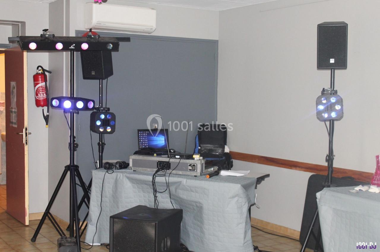 Matériel de sonorisation et d'éclairage installé dans une salle avec table de mixage, enceintes et projecteurs lumineux.