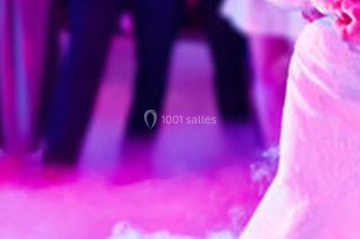 Salle de réception décorée avec des lumières violettes, tables dressées et écran affichant des prénoms.