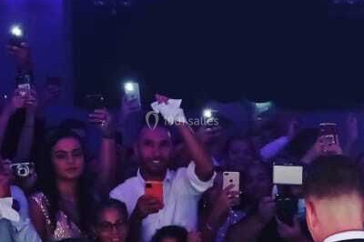 Salle de réception décorée avec des lumières violettes, tables dressées et écran affichant des prénoms.
