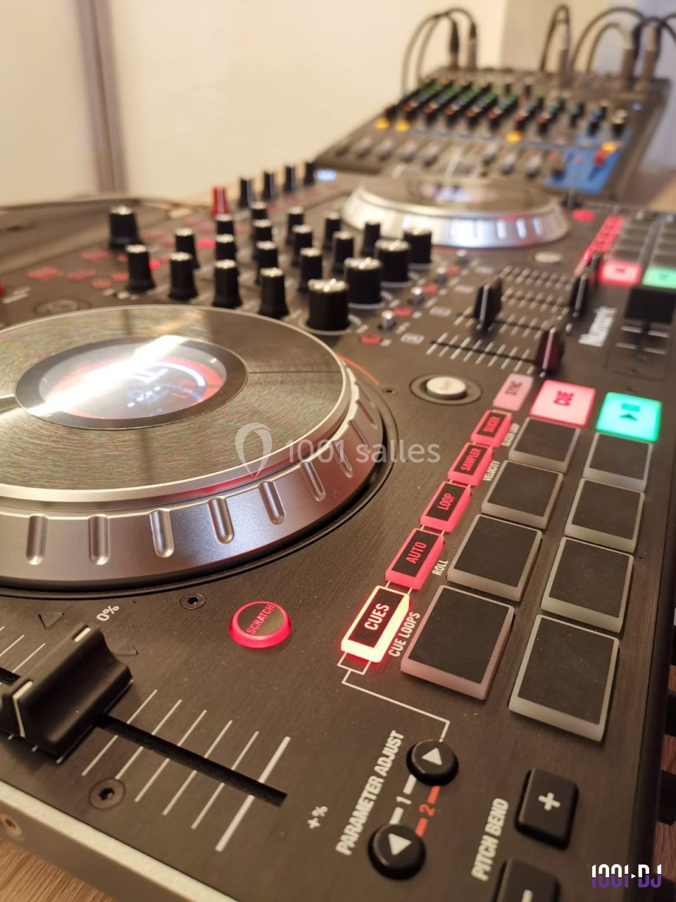 Table de mixage DJ avec platines, boutons et curseurs, connectée à une console audio en arrière-plan.